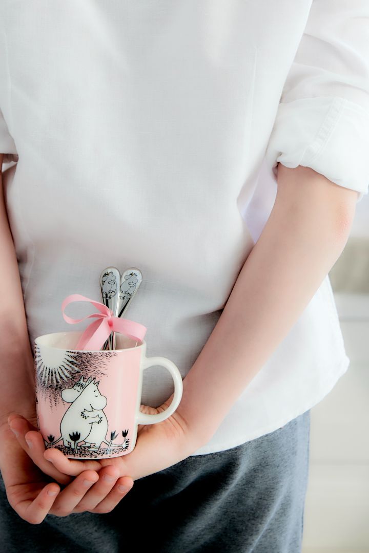 En dreng gemmer Mumi-koppen 'Love' af Moomin Arabia med Mumi-skeerne 'Love' af Hackman bag sin ryg.