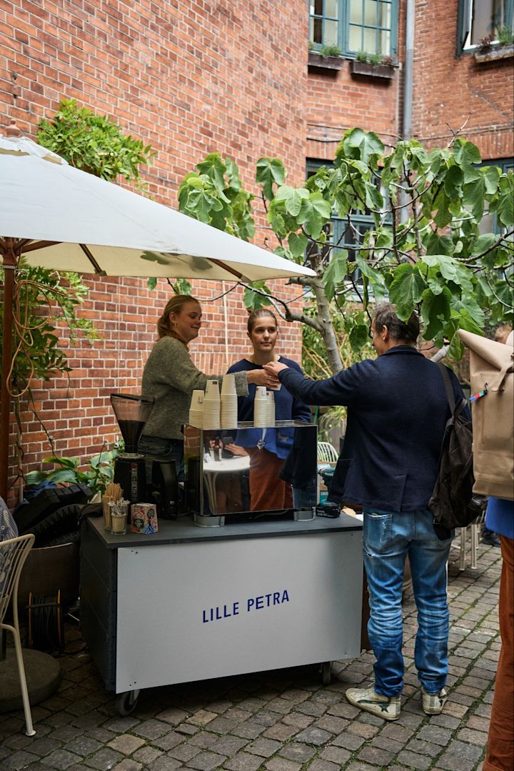Stop ved Lille Petra Cafe på din byrundtur i København for designelskere. Her ser du personalet dele kaffe ud i gården. 