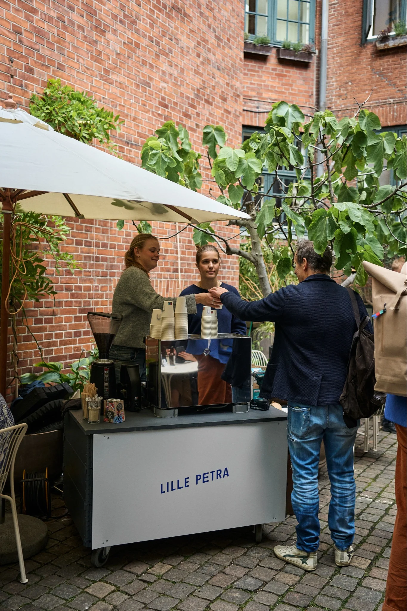 Stop ved Lille Petra Cafe på din byrundtur i København for designelskere. Her ser du personalet dele kaffe ud i gården.