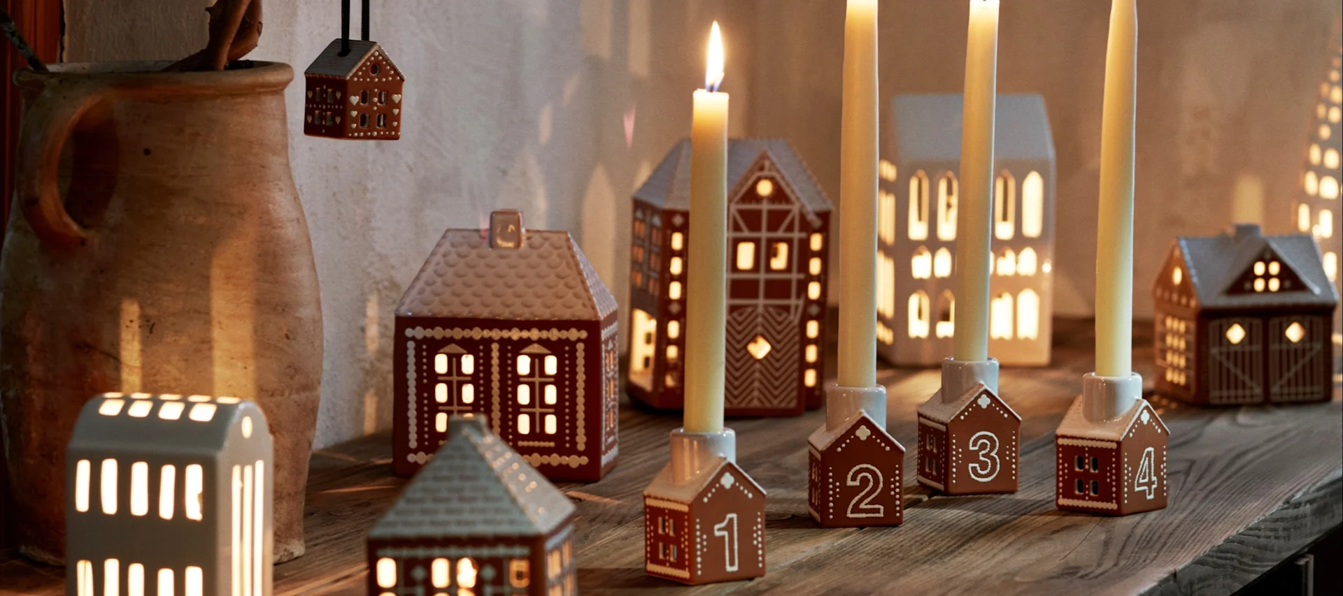 Sådan pynter du op med traditionelt skandinavisk julepynt - her ser du en ung dreng, der spiser et peberkagehus i vindueskarmen omgivet af andre lysestager i peberkagehusstil.