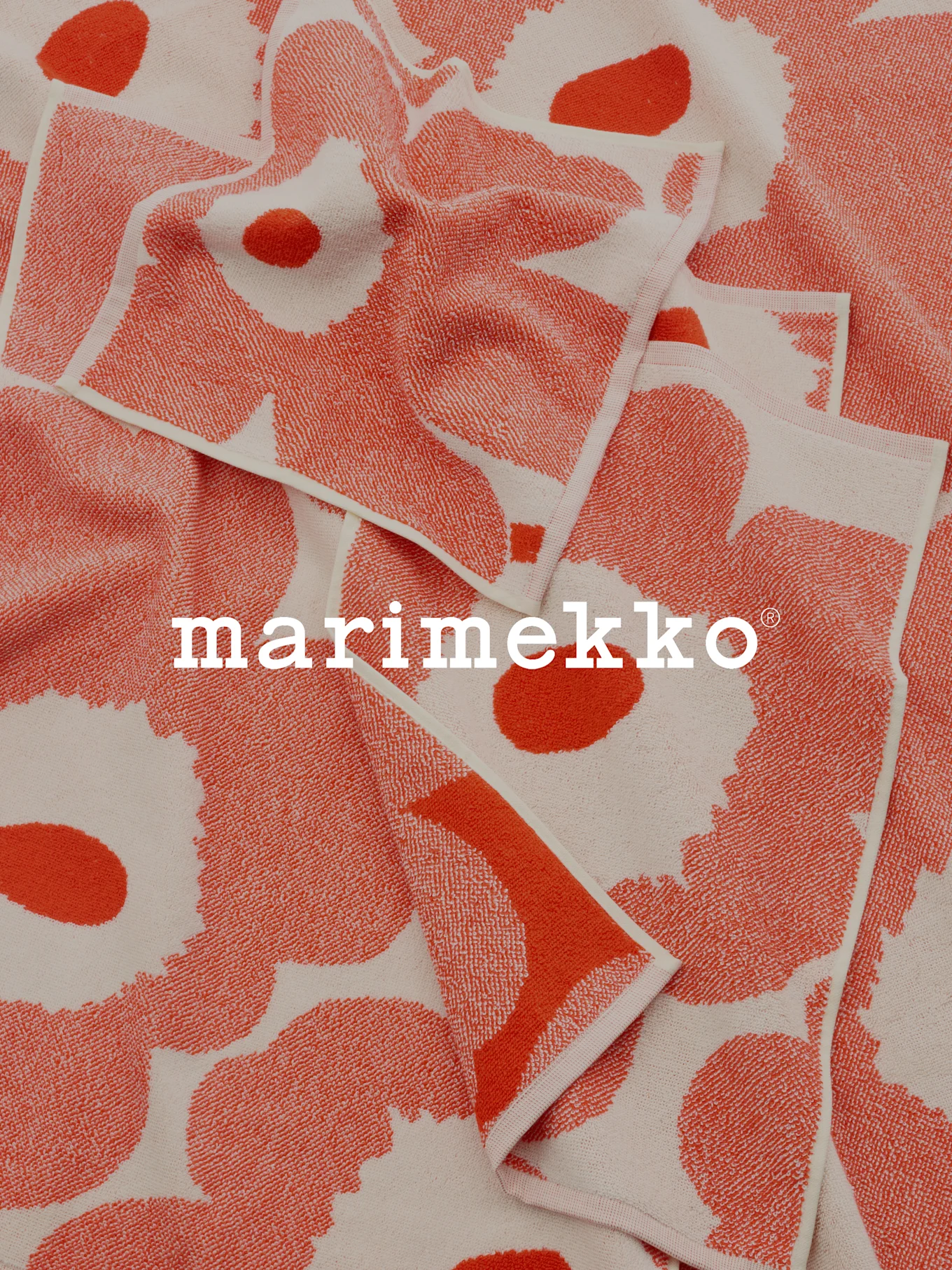 Foldede koral- og råhvide mønstrede håndklæder med Marimekko-logo.