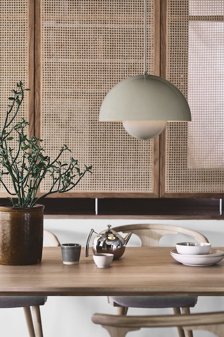Nyd Japandi trenden med simpelt, stilrent tilbehør som VP7 Flowerpot loftlampen fra &Tradition i greige, her ser du den hænge i en stue med en rotting væg.