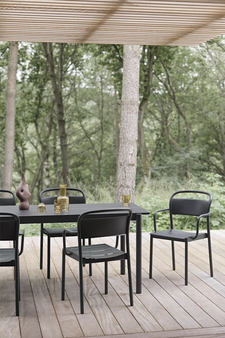 En overdækket træterrasse med bord og stole i sort fra Linear-kollektionen fra Muuto.