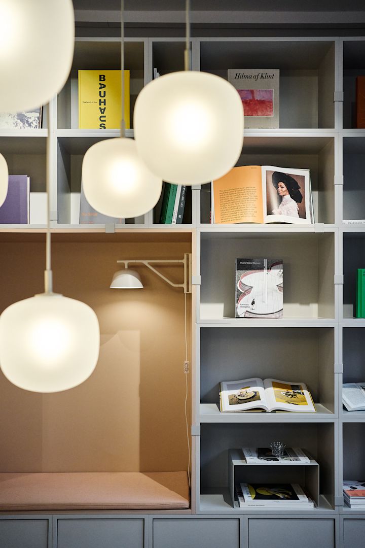 En pæn hylde dekoreret med bøger, med flere Rime-pendler fra Muuto hængende i forgrunden.
