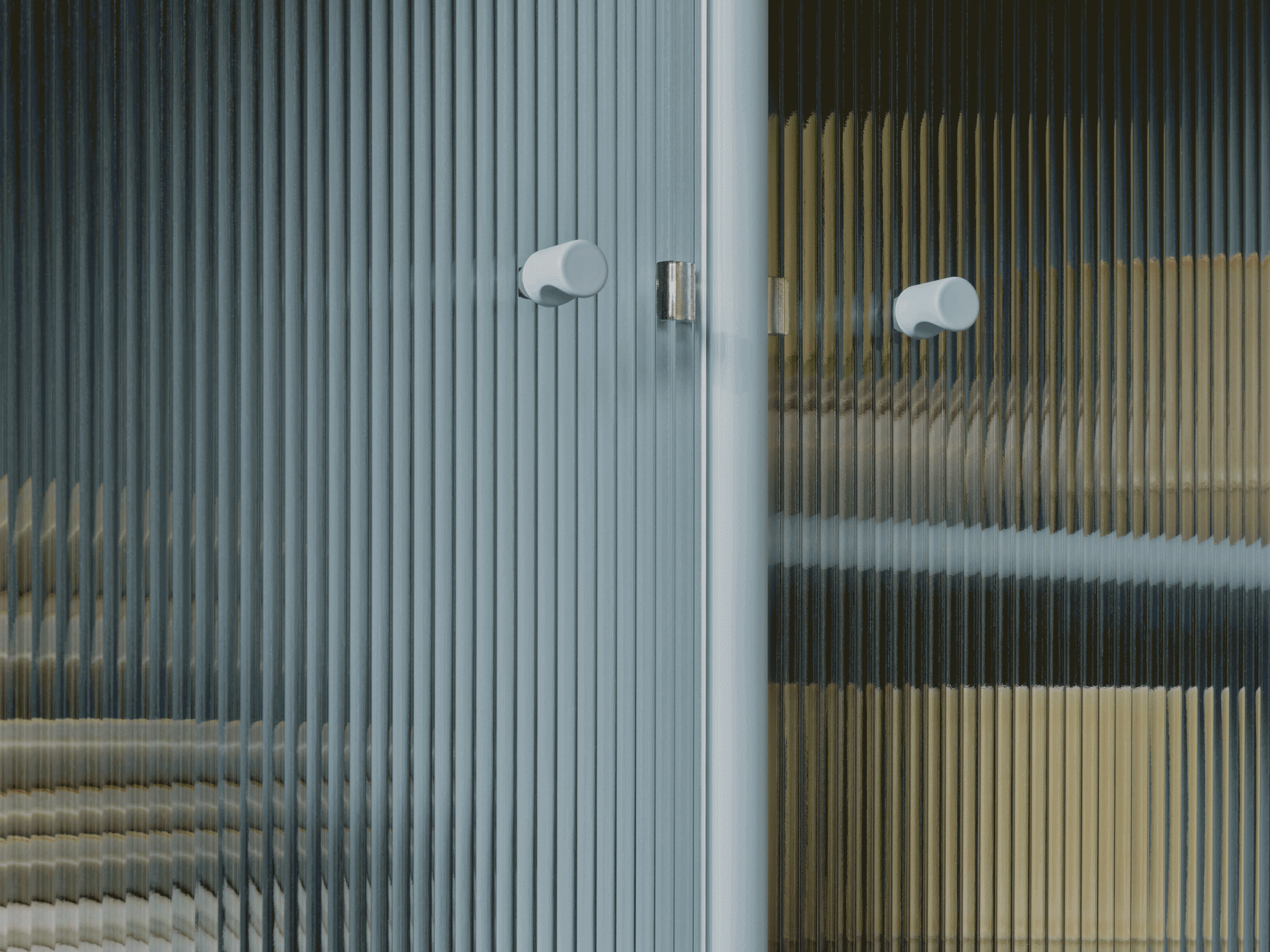 Nærbillede af riflet glasdør med to lyse runde håndtag, viser forvrængede farver gennem gennemsigtig tekstur.