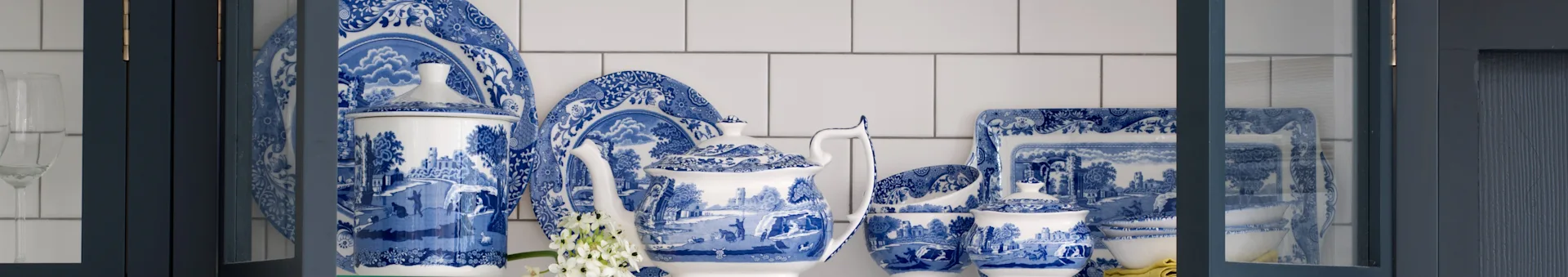 Blåt og hvidt mønstret porcelænsstel med tekande, tallerkener og skåle i et mørkeblåt skab.