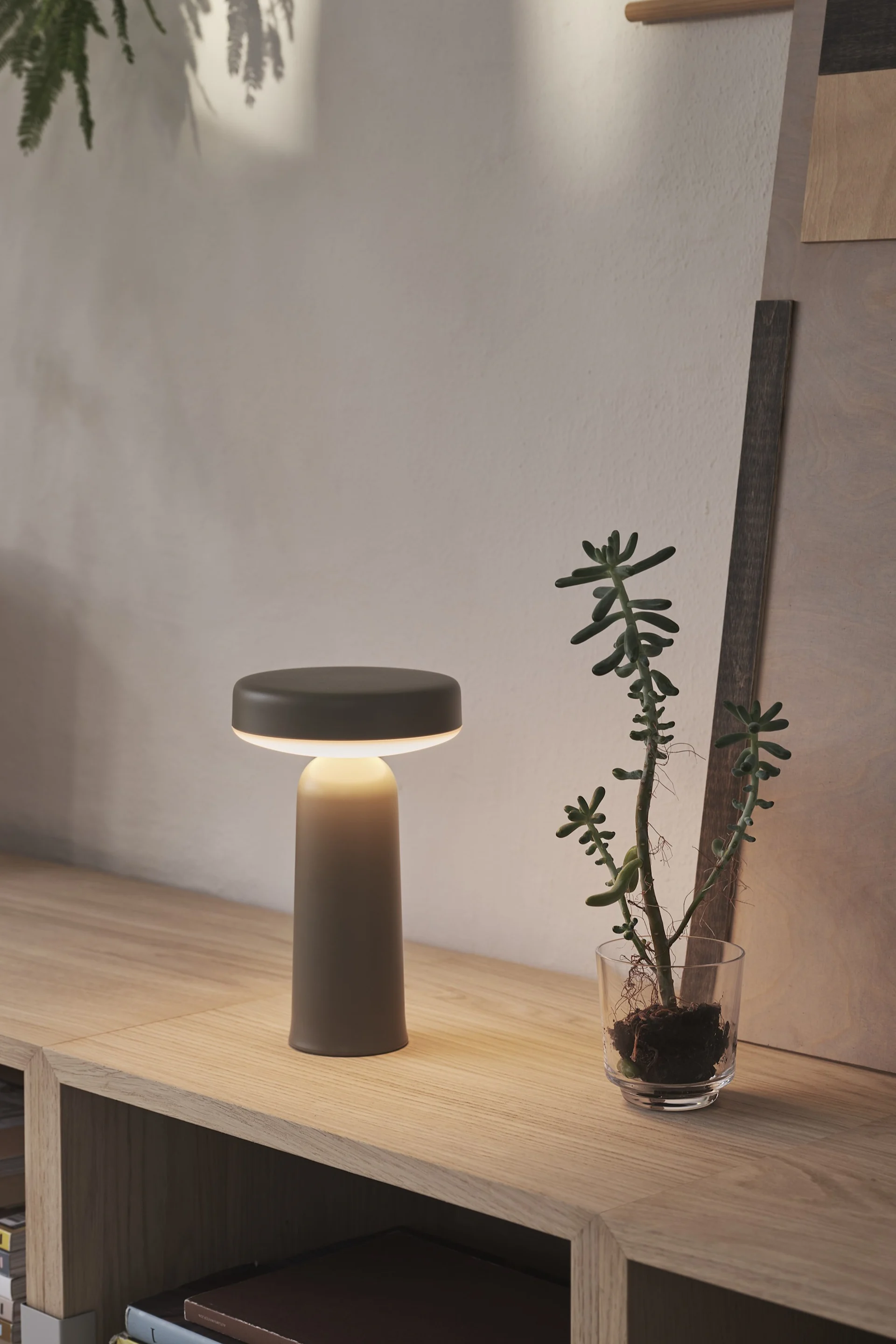 Den sølvfarvede, transportable Piton-bordlampe fra Muuto hænger på en af fire kroge på væggen.