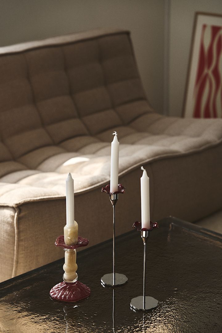 Lara lysestage fra Byon, her på et sofabrod med en glasskive, lavet i farvet glas i beige og vinrød, designeren er inspireret af romerske søjler.