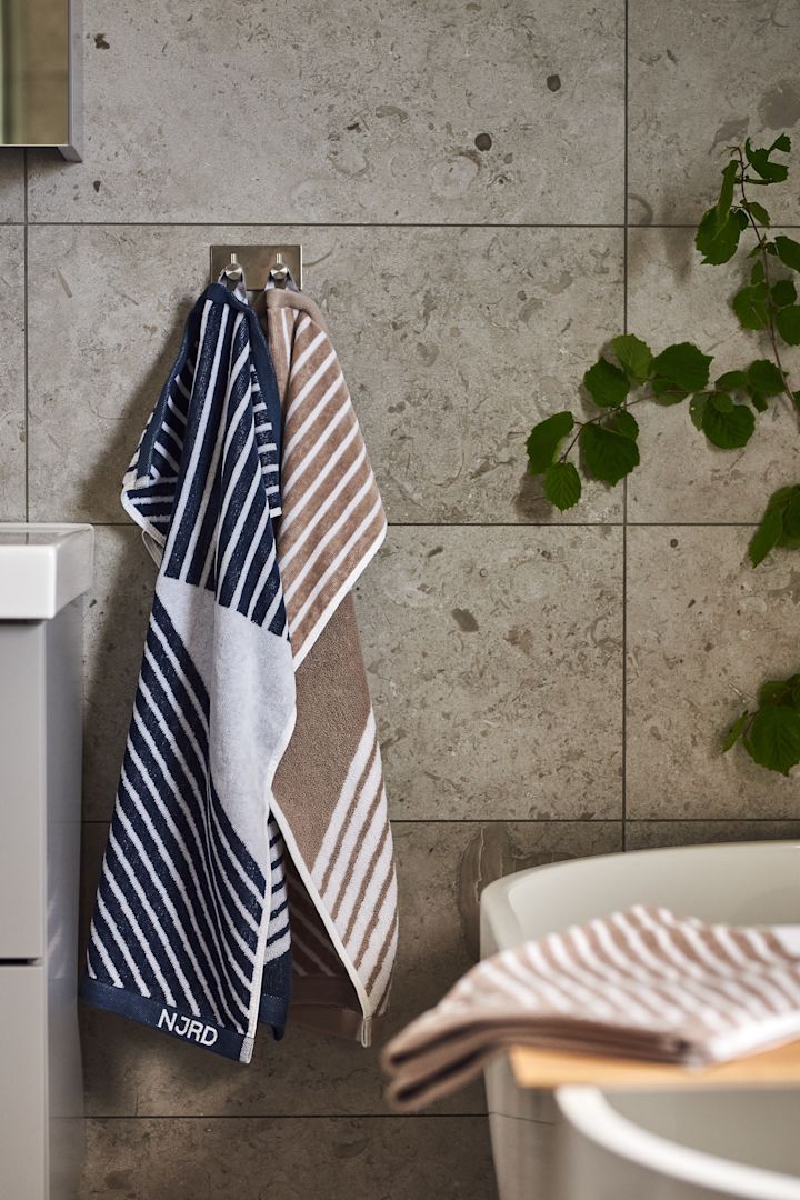 Skab et hjemmespa på badeværelset ved brug af de bløde Stripes håndklæder fra NJRD i beige og blåt for afslappende stunder.
