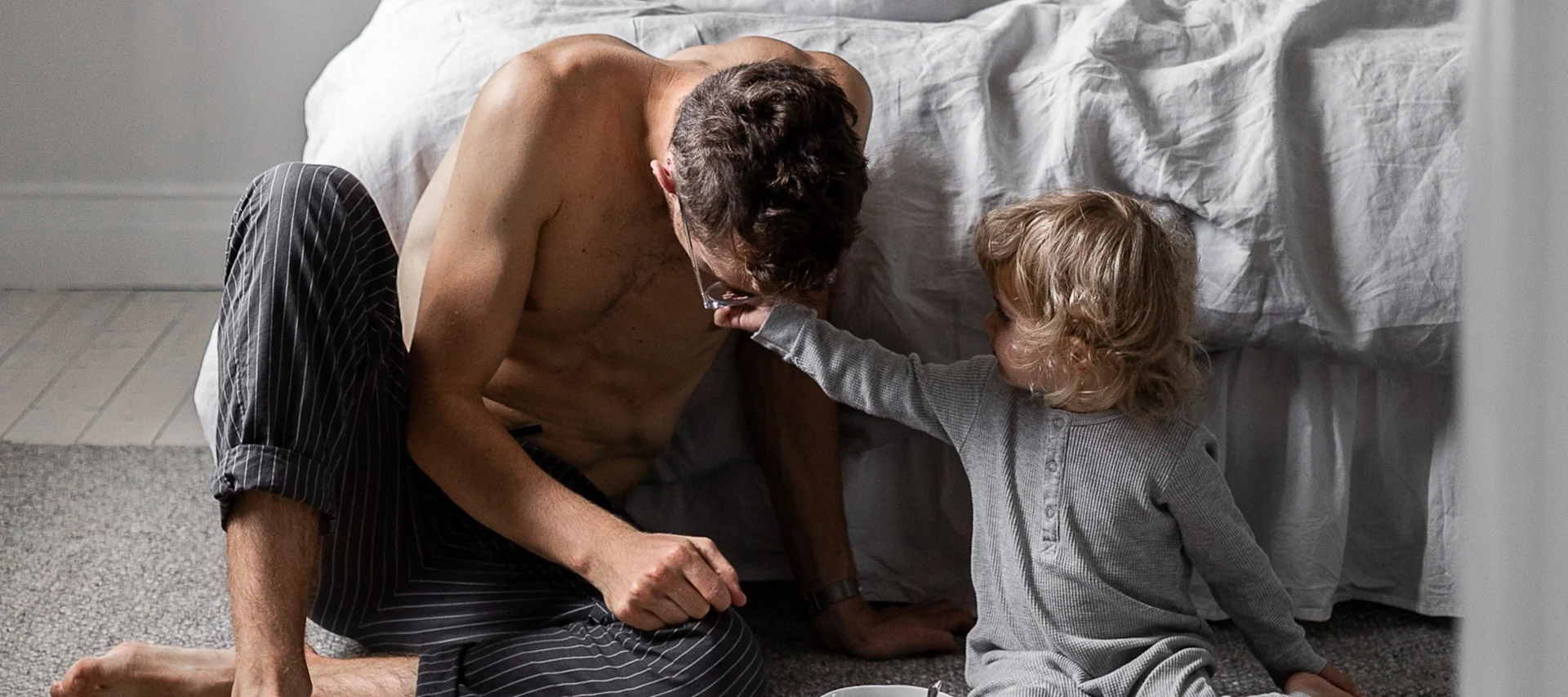 Her kan du se en mand med et lille barn som sidder foran en seng.