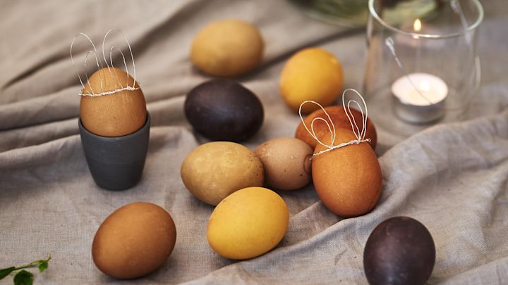 Farv æggene naturligt med ingredienser som gurkemeje og kaffe for at få påskeæg i diskrete nuancer af gul og brun, og lav søde kaninører af ståltråd til pynt.