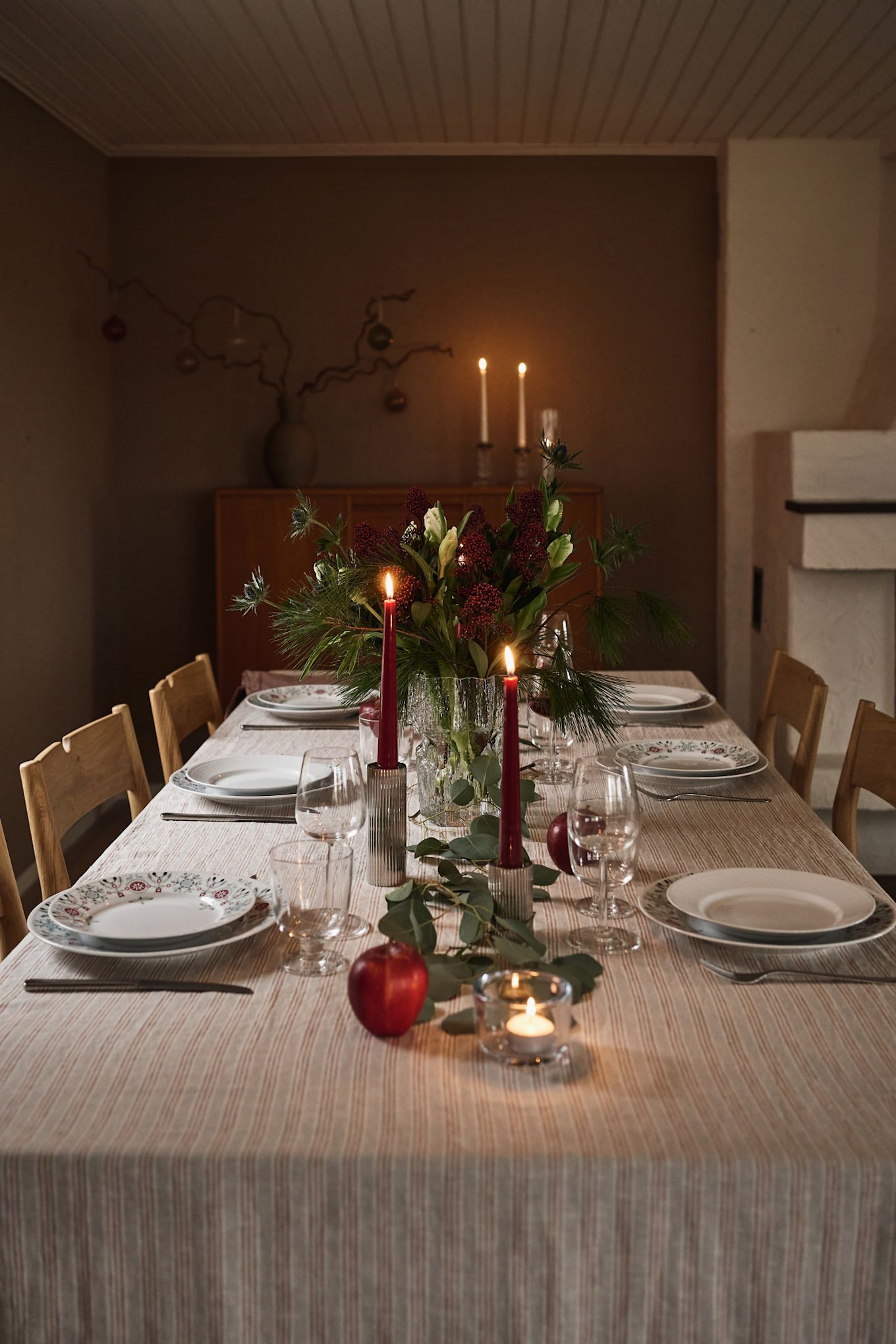 En stemningsfuld og enkel juleborddækning med røde stearinlys og printet julestel. 
