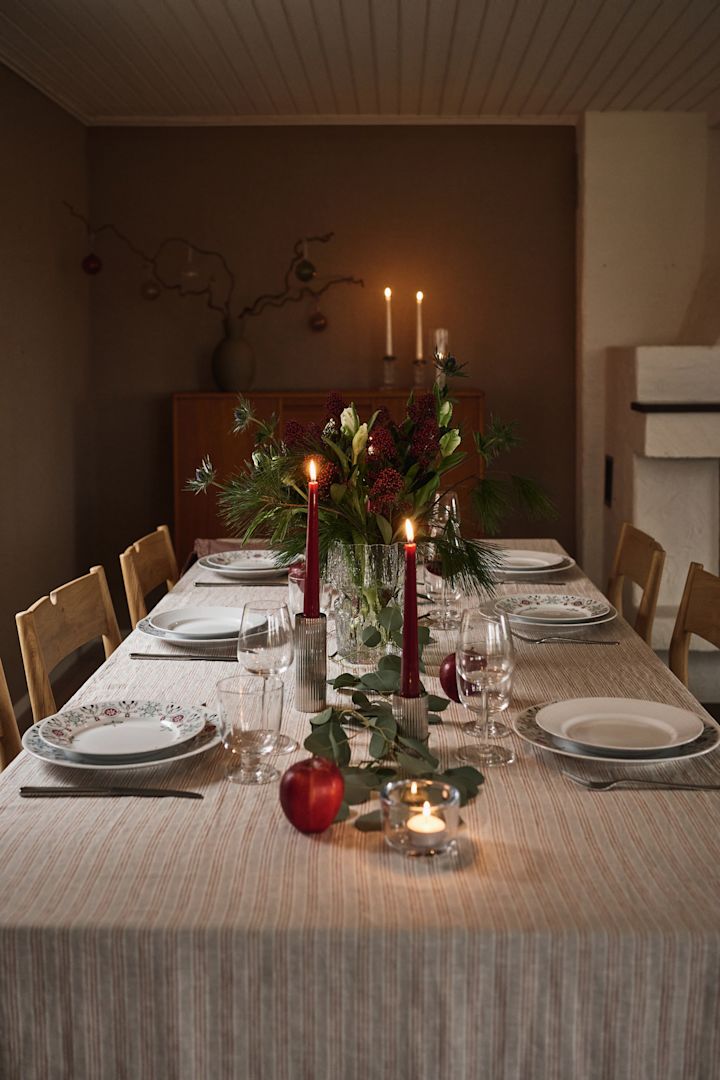 En stemningsfuld og enkel juleborddækning med røde stearinlys og printet julestel. 