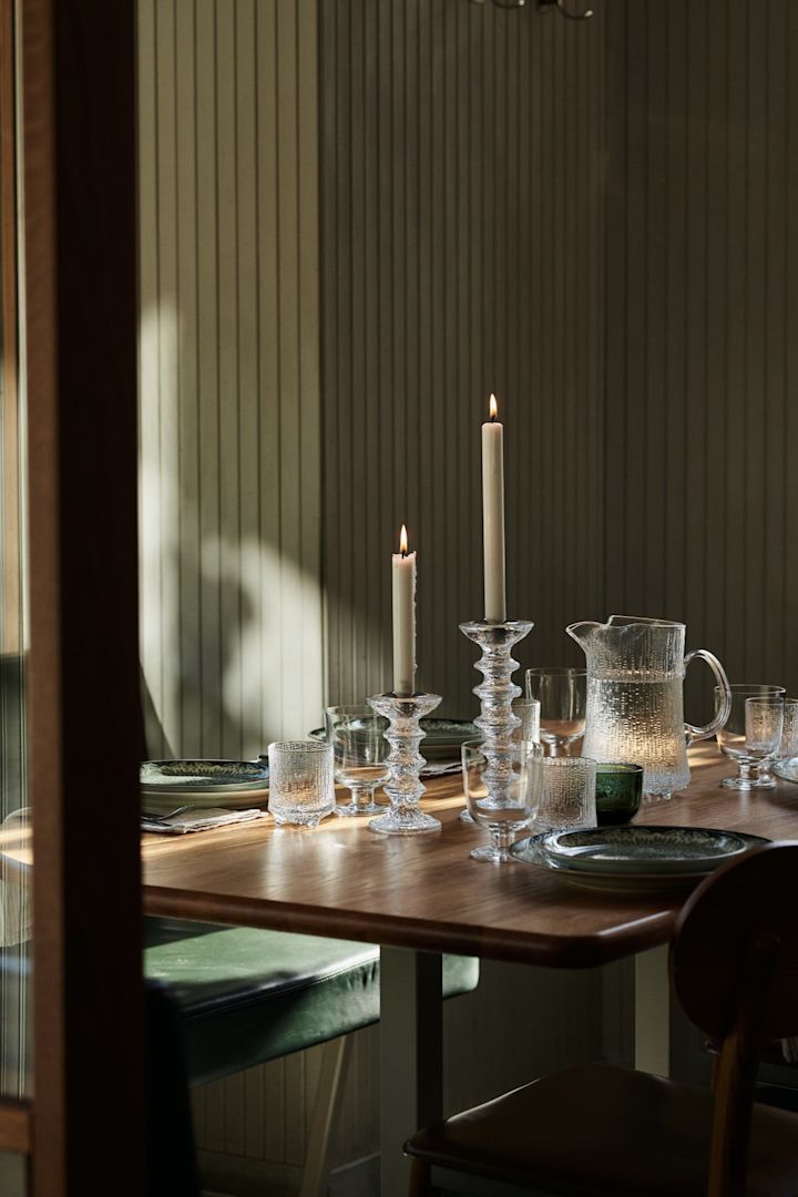 Her ser du en borddækning i et restaurantmiljø med grove lysestager i glas og matchende vandkande.