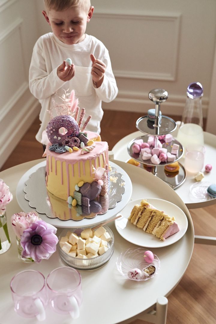 Et påskedessertbord er en god idé til en farverig og sjov borddækning i påsken. Her ser du en lille dreng, der nyder et stykke kage. 