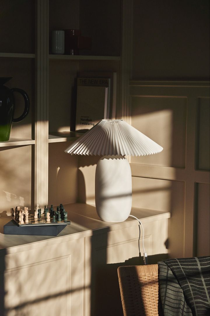 Opfrisk dit hjem med disse moderne belysningsideer. Her ser du den teksturerede Boulder-lampe fra Scandi Living i en bogreol badet i sent eftermiddagslys. 
