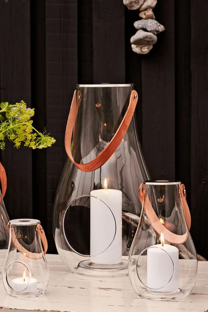 Udendørs lanterner og stormlygter placeres bedst i grupper. Her kan du se Design with Lights-lanternen fra Holmegaard i forskellige størrelser.