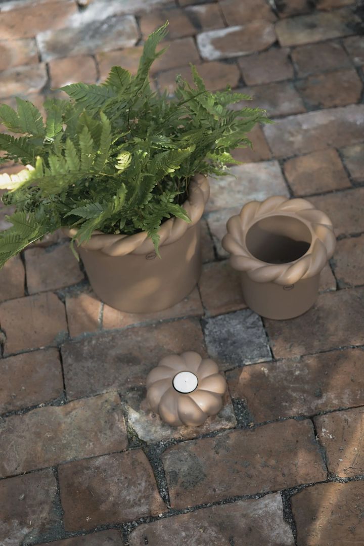 Twine potter fra DBKD har et moderne design i stentøj, hvor potterne har en bred flettet kant i toppen, som giver potterne et rustikt look. Her to krukker i brun ved siden af hinanden på en brolagt terrasse.