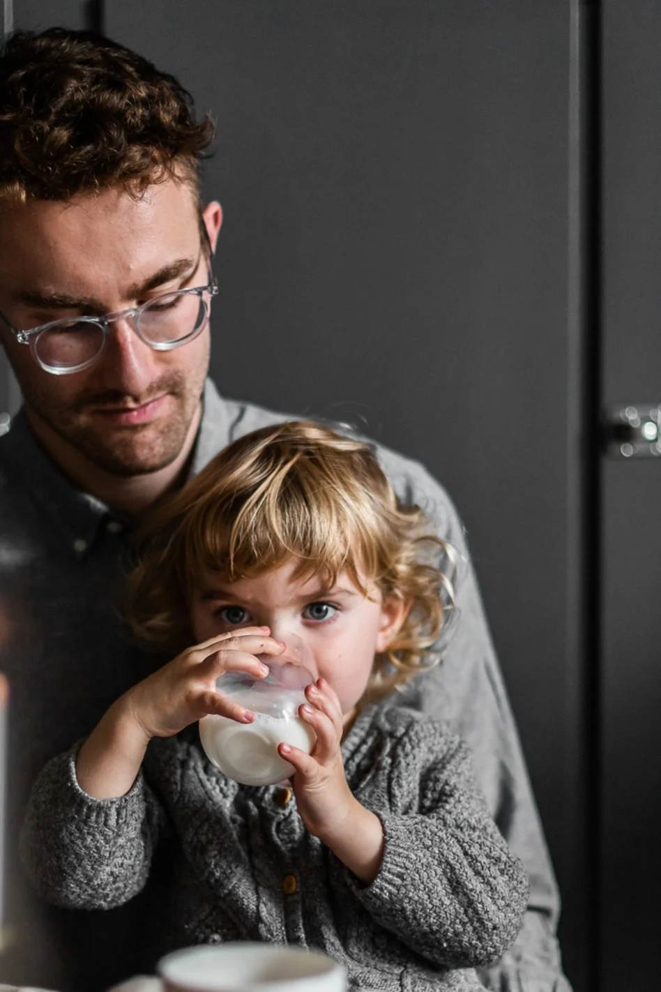 Gaveidéer til fars dag. Tid sammen er altid den med værdifulde gave til fars dag. Her ses et barn der sidder på sin fars skød og drikker af et glas fra Scandi Living.