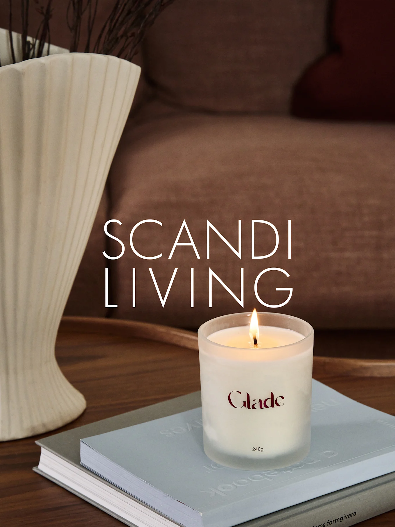 Et brændende Glade-lys på bøger, ved siden af en riflet vase med grene. Overlay-tekst: SCANDI LIVING.