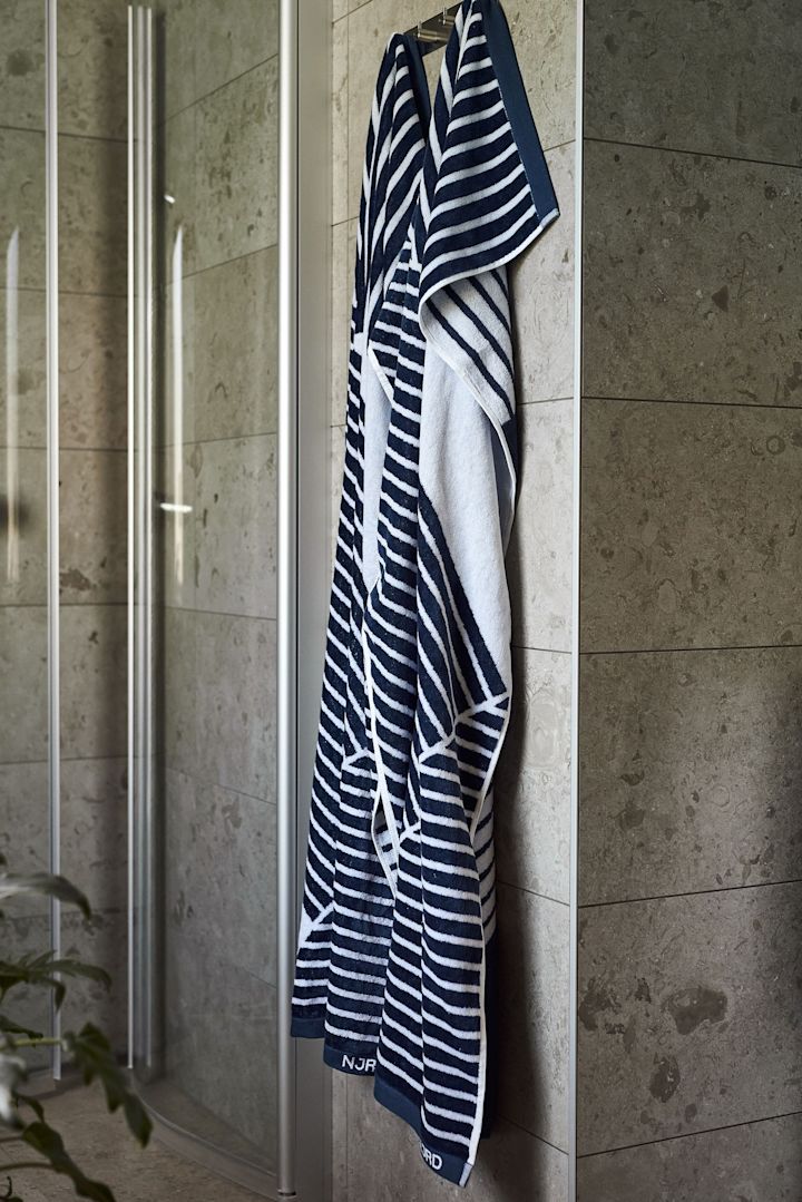 Giv Stripes-badehåndklædet fra NJRD som fars dags gave til saunaelskere, her hængende foran en bruser. 