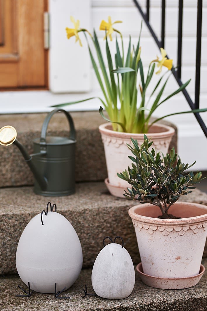 Betonpåskekyllinger fra DBKD står på trappen sammen med grønne planter i potter fra Bergs Potter. 