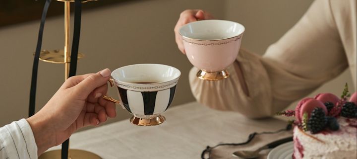 Fejr Galentine's Day med en traditionel eftermiddagste med dine veninder. Her kan du se to venner der har løftet tekopper i en traditionel tekopform fra Hilke.