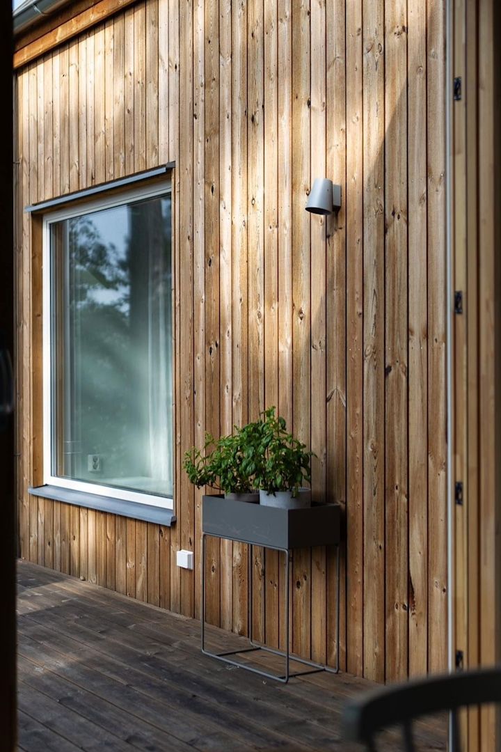 Her ser du den sorte metalplantekasse fra Ferm Living stå på terrassen til et svensk træhus.