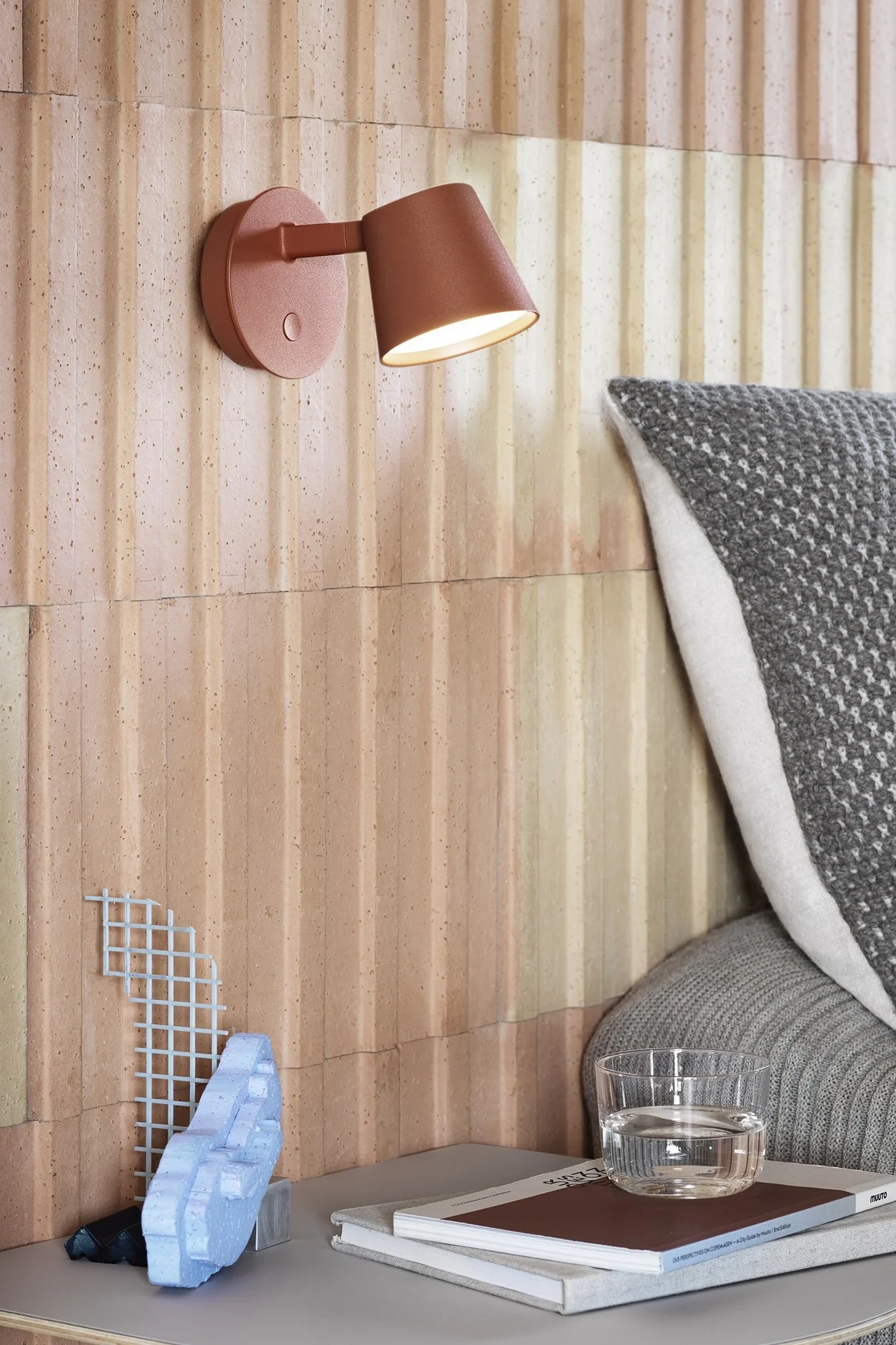 Moderne belysningsideer til at opdatere dit hjem omfatter stilfulde væglamper som Tip-væglampen fra Muuto, der ses her i rød, monteret over et natbord. 