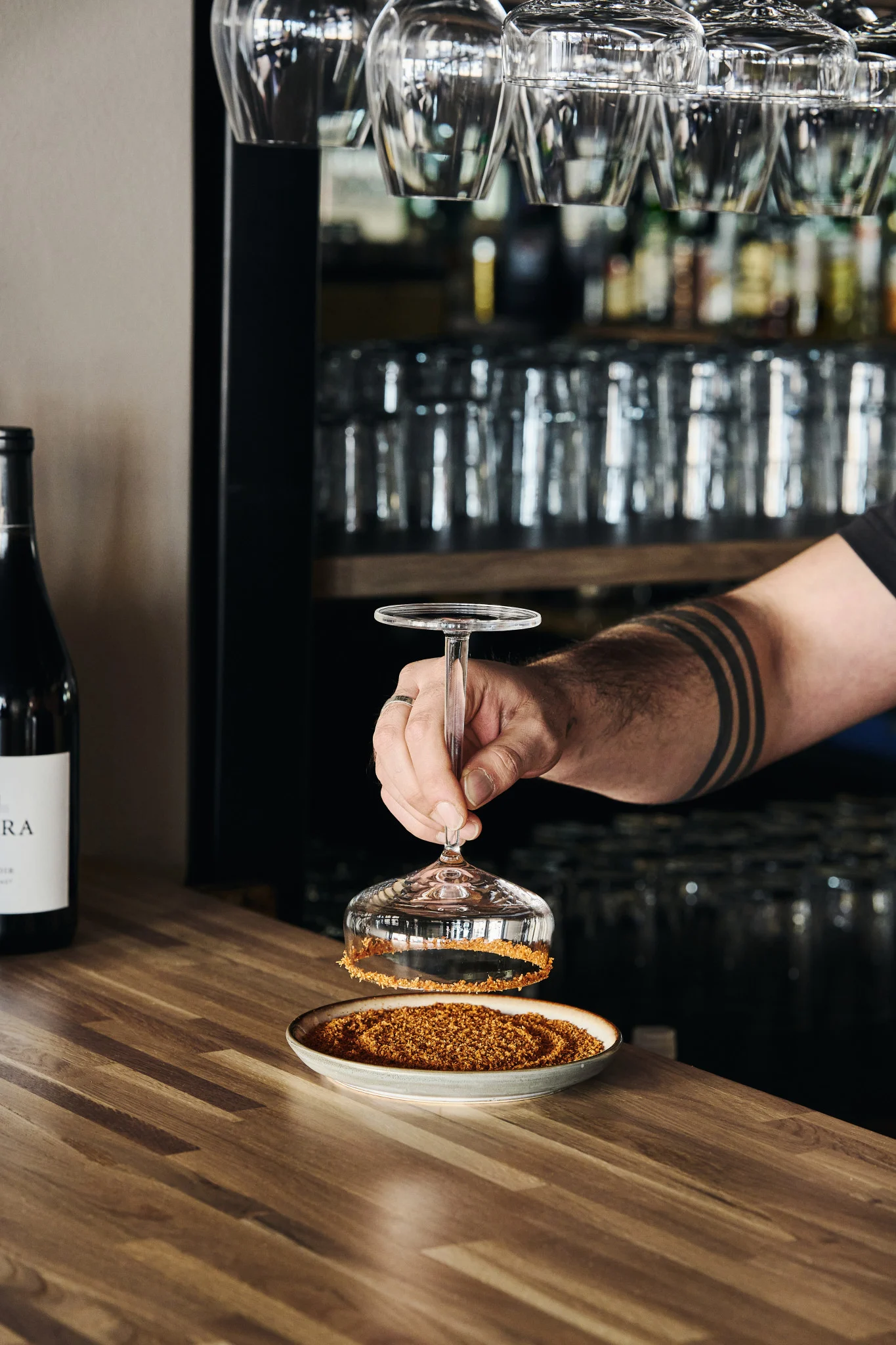 En hånd dypper kanten af et margarita-cocktailglas i saltblandingen for at give drinken ekstra smag. 