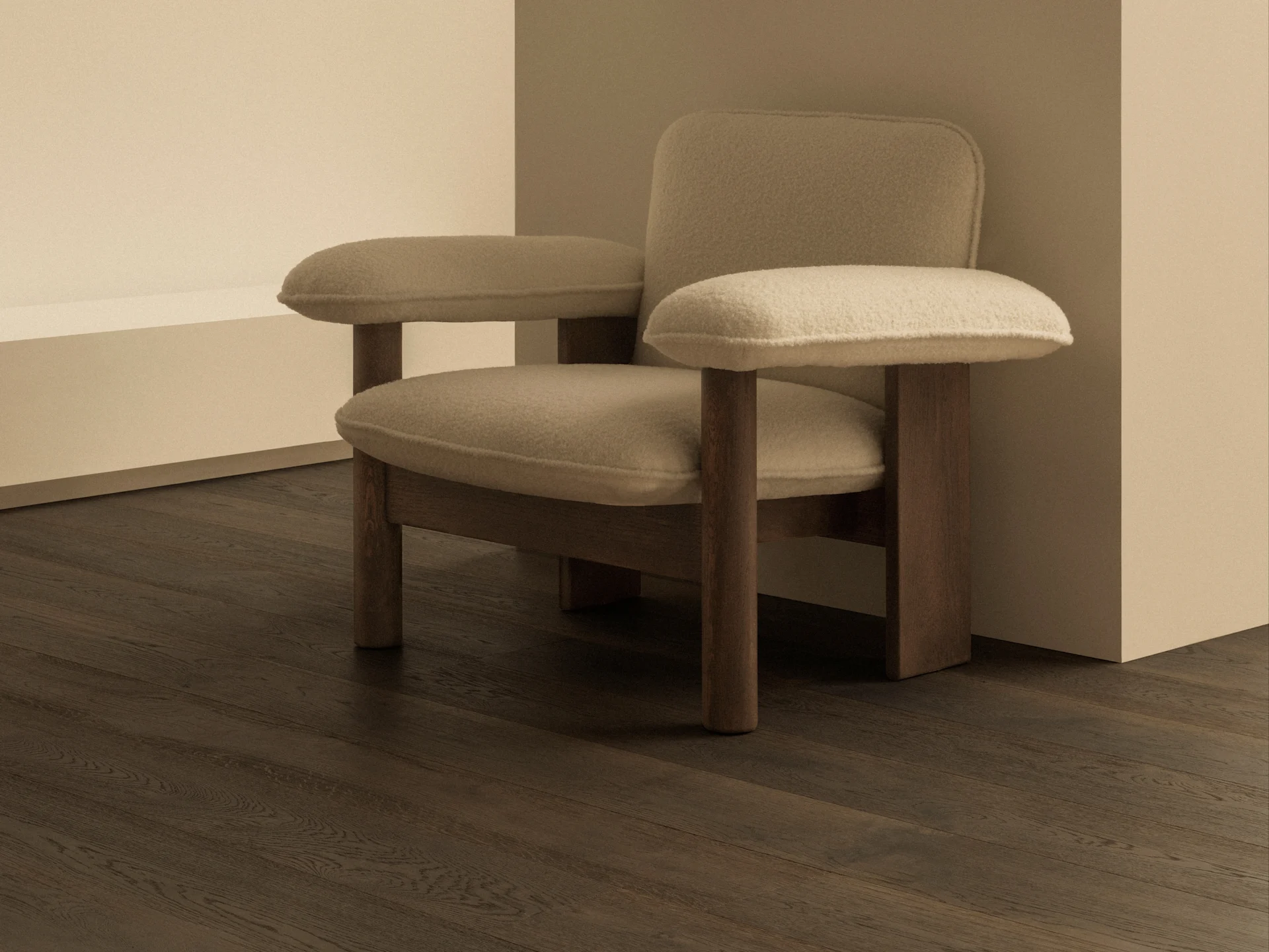 Et minimalistisk rum med en beige polstret lænestol, mørke trægulve og en moderne messingvæglampe med en hvid kugleskærm.