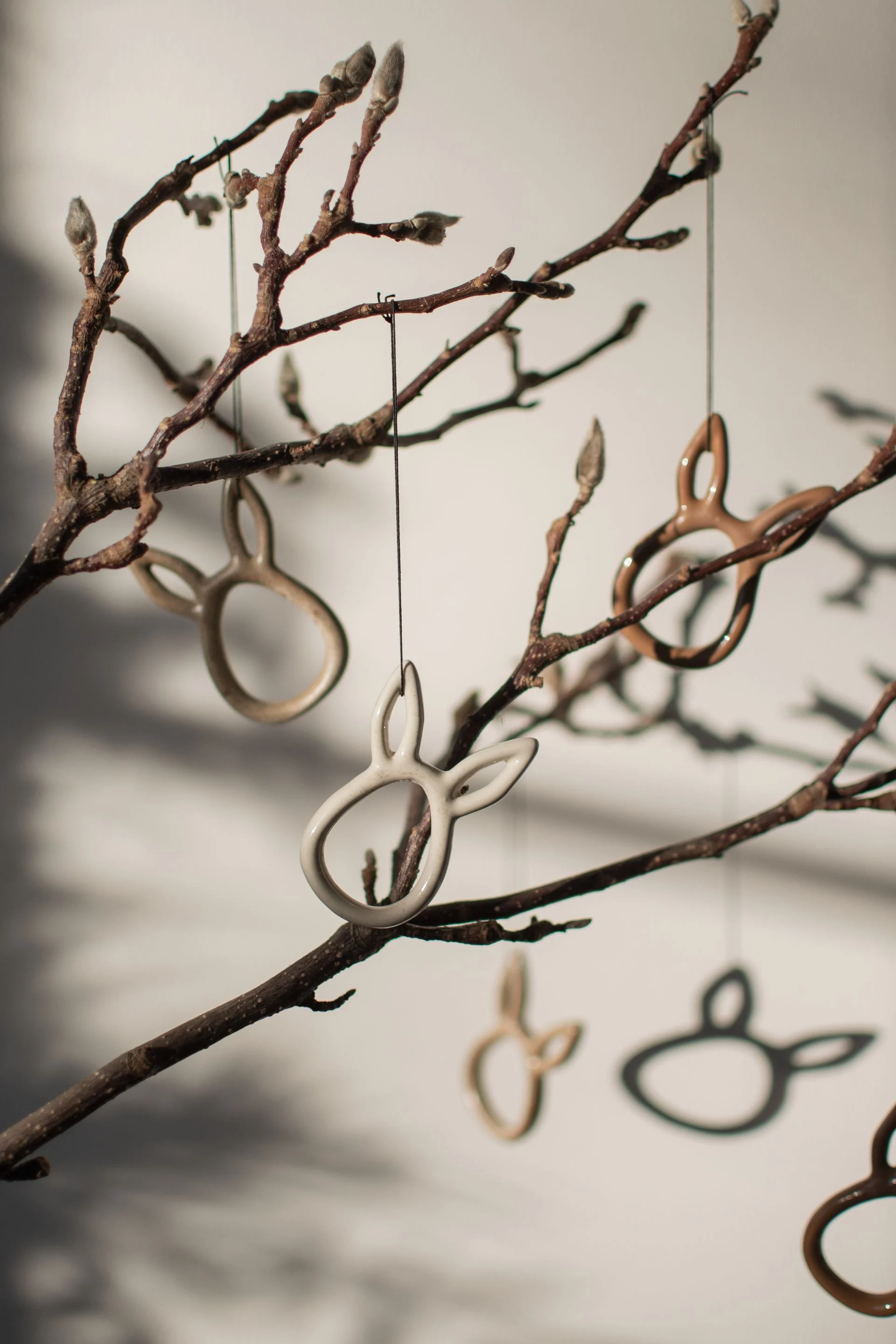 De kaninformede Sprinkle rabbit-påskevedhæng fra DBKD hænger fra en busk.