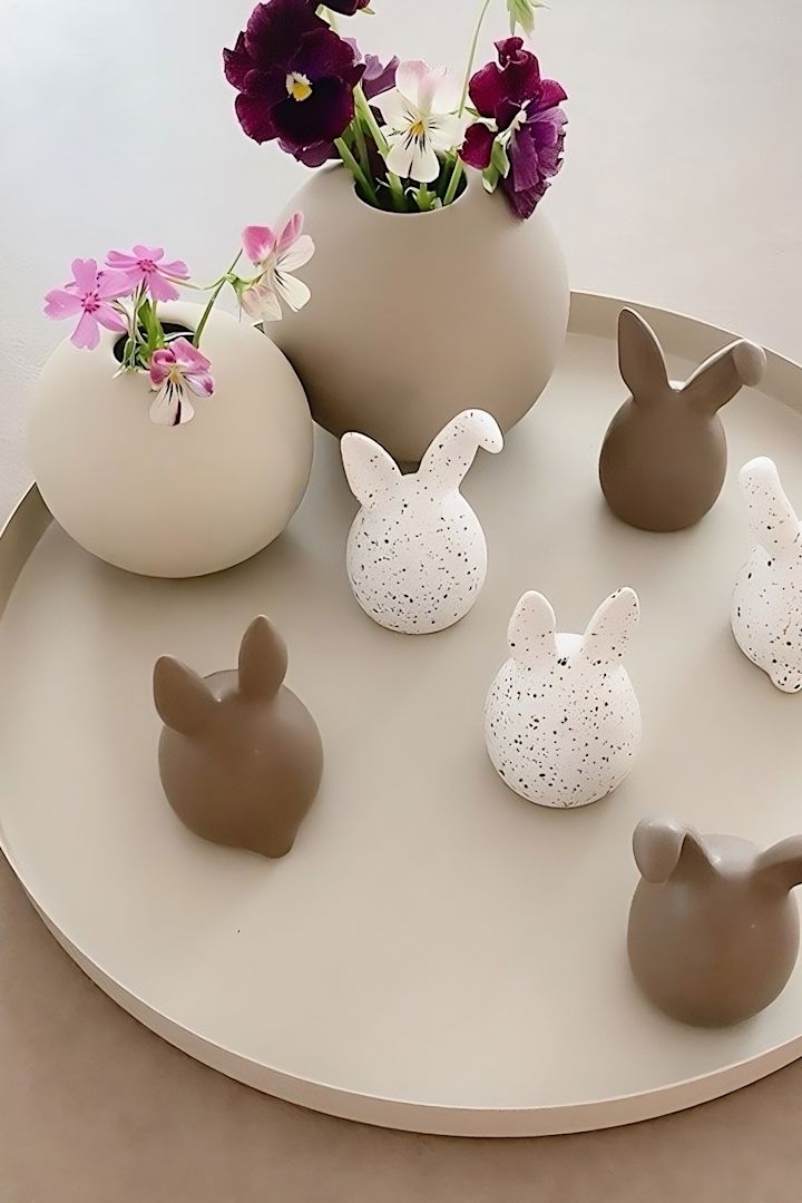 Trillinger af tofarvede påskeharer fra DBKD står på en bakke ved siden af to kuglevaser fra Cooee Design i @sachi_roooms hjem.