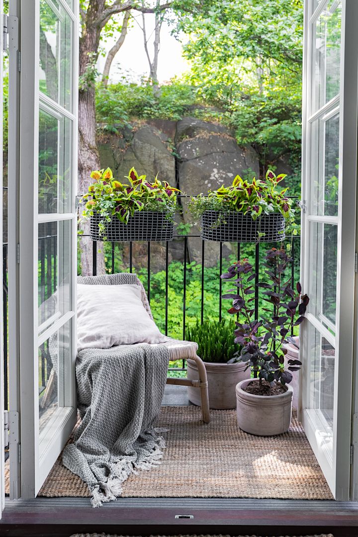 En lille, hyggelig altan med en armstol og flere forskellige planter, plantet i blandt andet Korbos altankurv.
