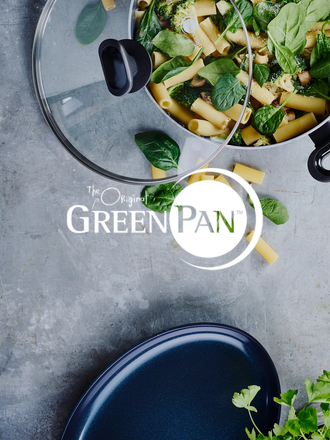 Pasta med spinat og broccoli i en pande, med et glaslåg og 'GreenPan'-logoet synligt.