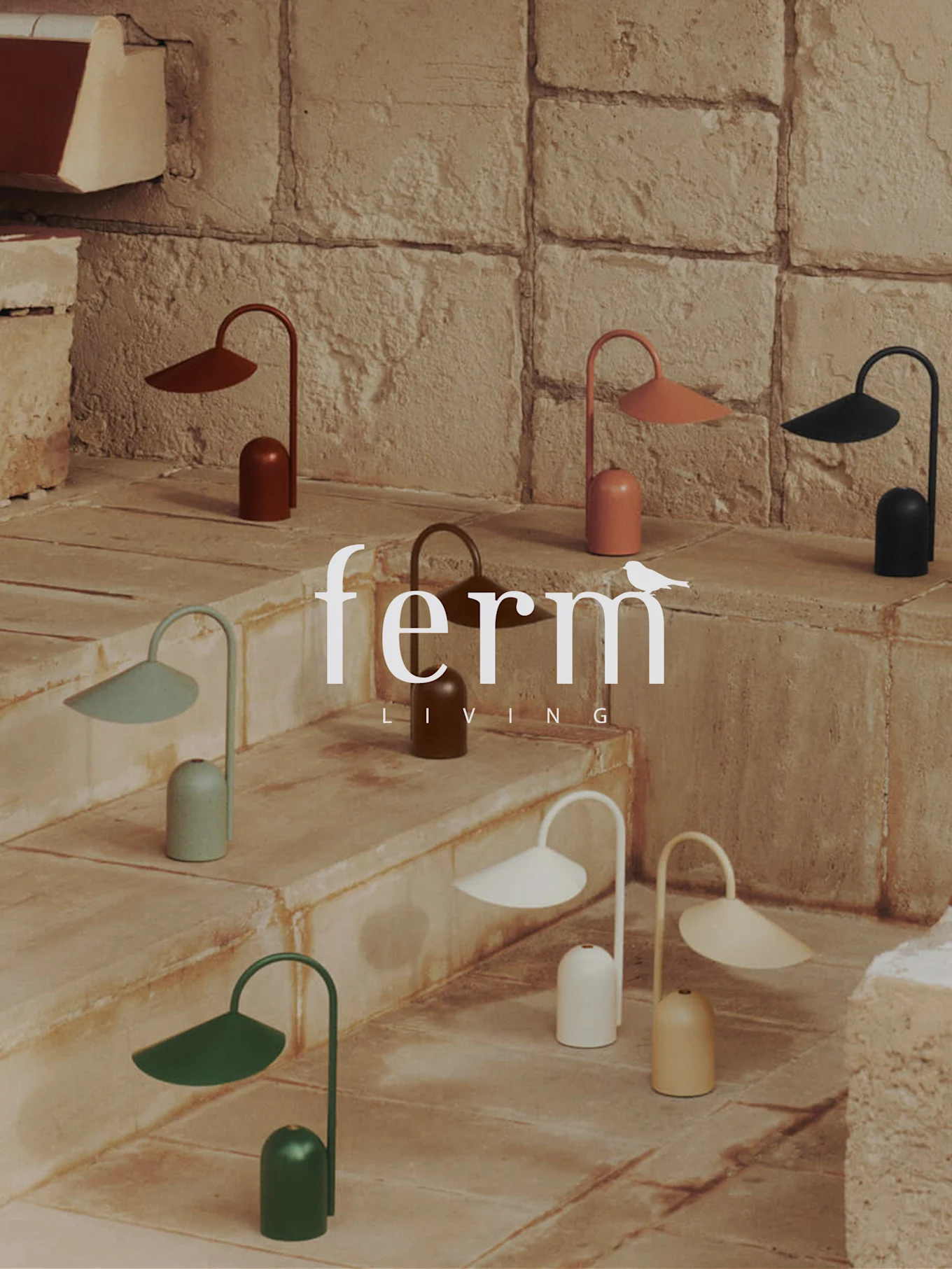 Samling af små, farverige moderne lamper med klokkebaser og buede skærme, udstillet på stentrapper. Ferm Living logo.