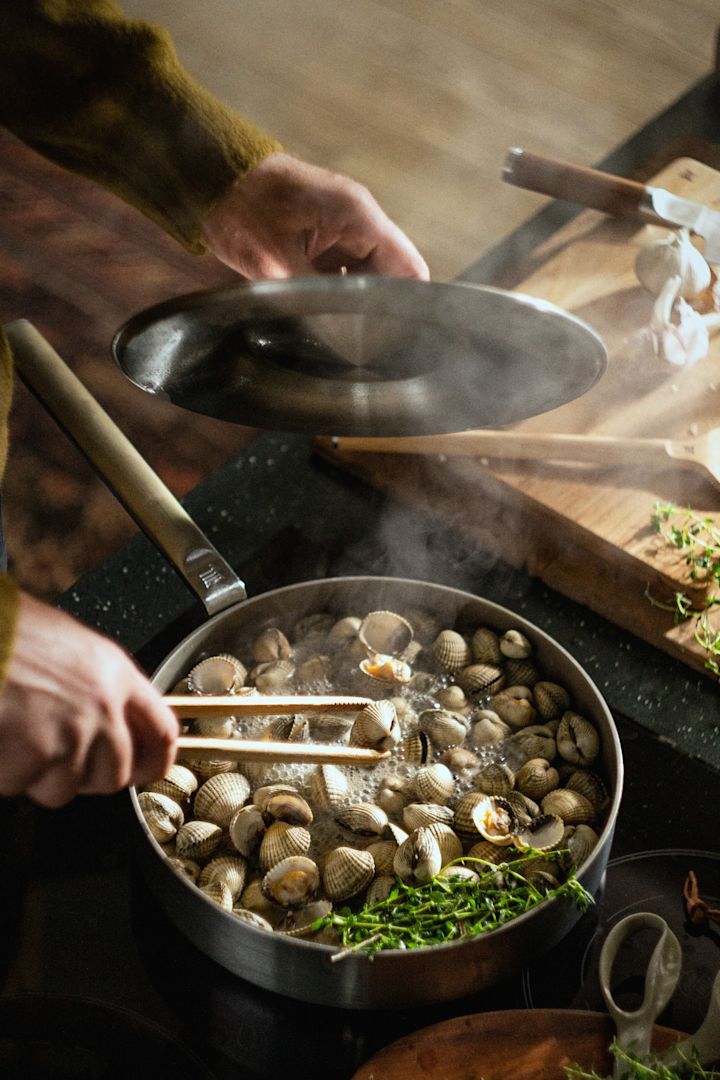 En person tilbereder muslinger i en rustfri stål Norden Steel sauterpande fra Fiskars.
