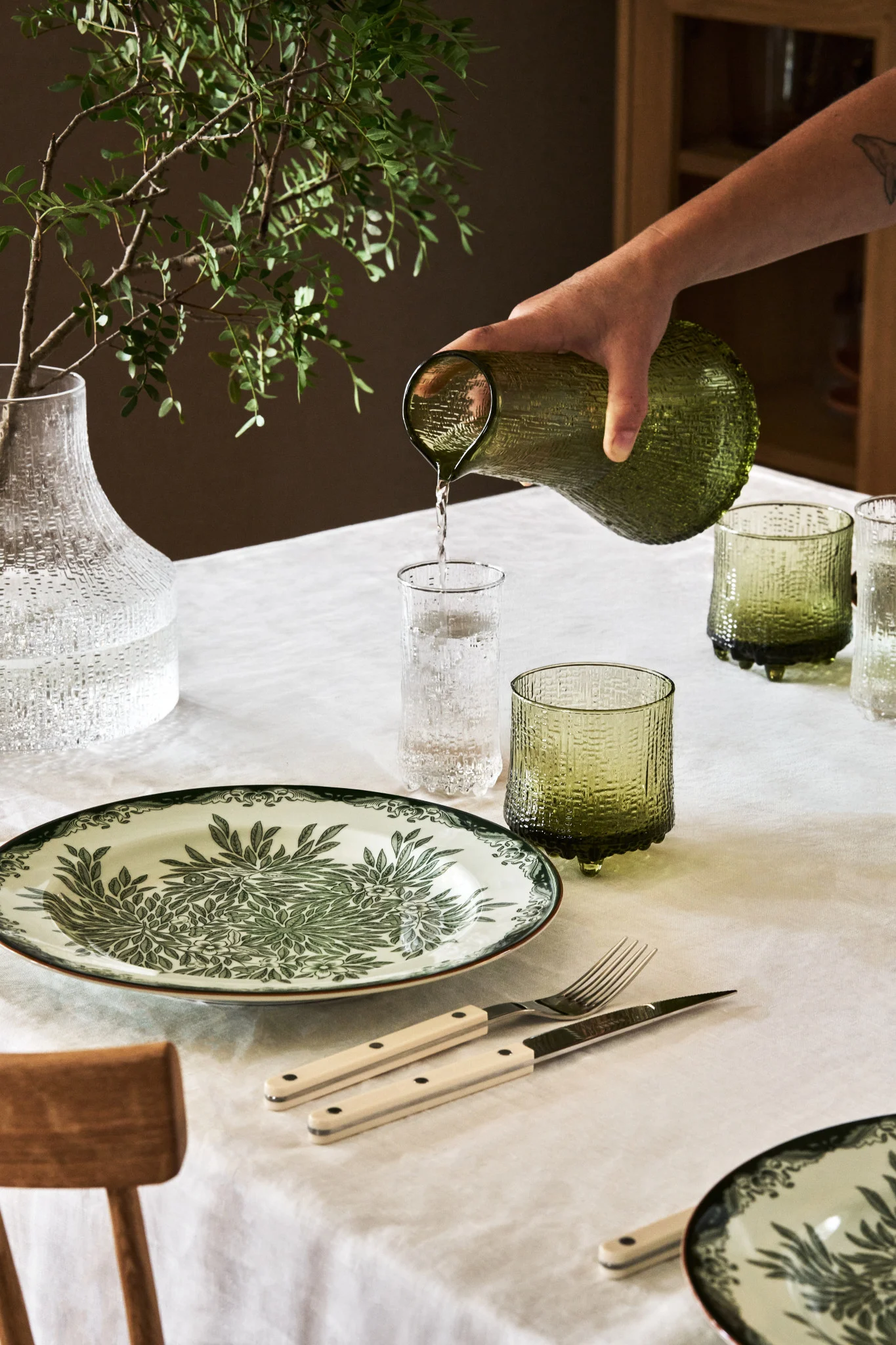 The Bag of Crisp vase fra HK Living er en unik og skulpturel vase i krom som passer perfekt til efterårets indretningstrender 2024, her stående på en lysebrun kommode.