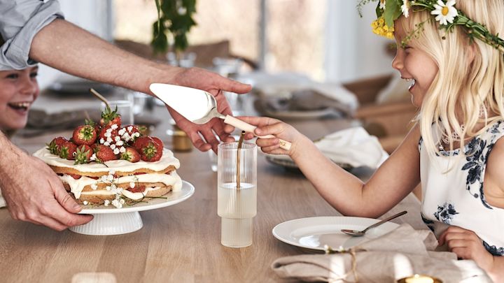 Et barn skærer den traditionelle midsommer jordbær kage.
